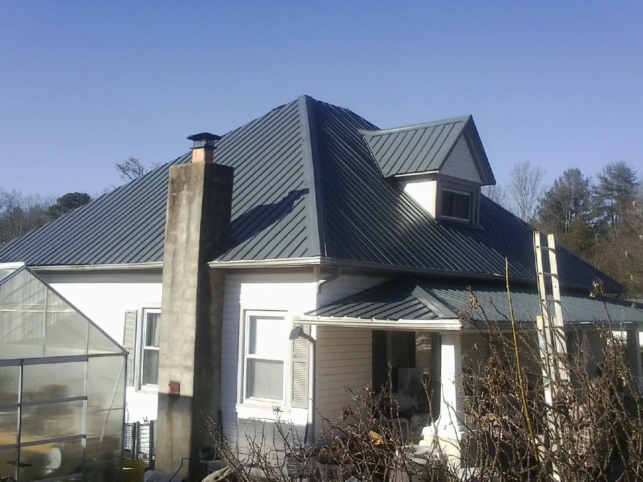 Dark blue standing seam metal roof on a white farmhouse with dormer — Slate & Tile Roof Repair by Roofing Brothers in Woodinville