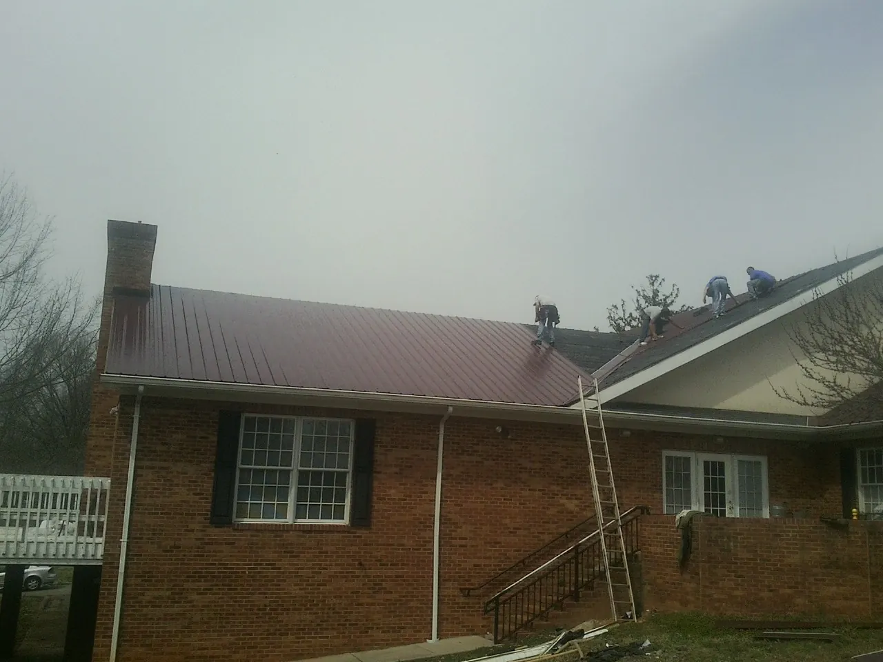 Crew setting red metal roofing panels on a brick home in Woodinville