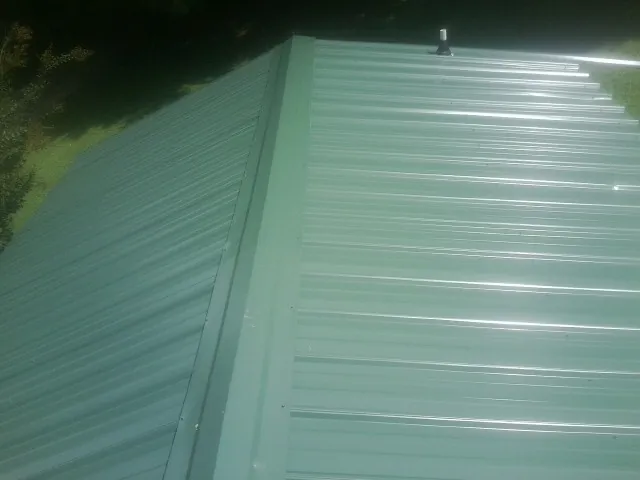 New green metal panels meeting at the ridge of a roof — Flat Roof Repair work by our crew in Woodinville