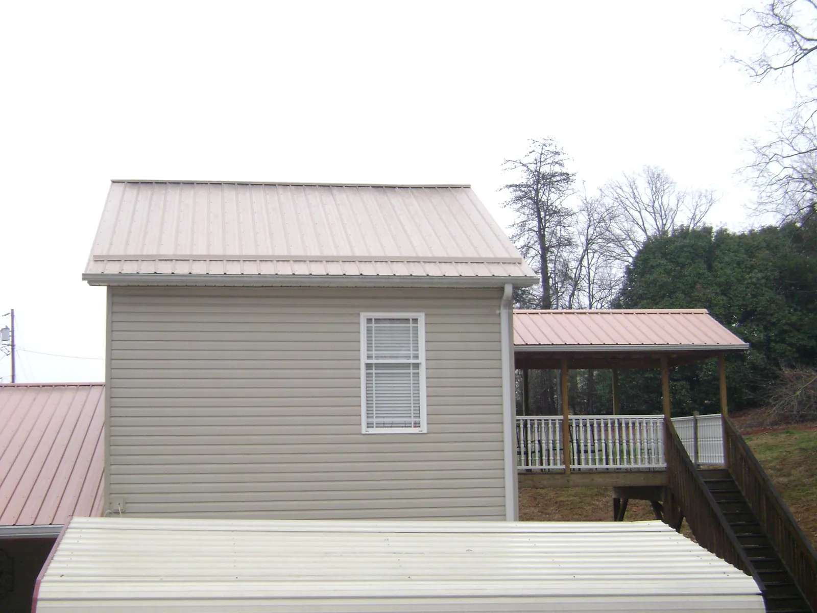 Tan metal roofs on a two story addition and attached porch, from a Roof Replacement job in Woodinville