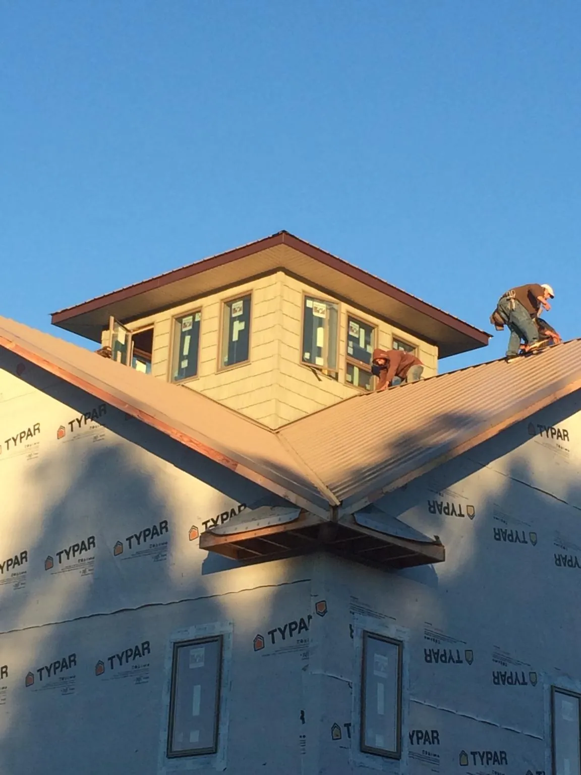 Roofers working around a rooftop cupola on a new metal roof at sunset — Roof Waterproofing in Woodinville by Roofing Brothers